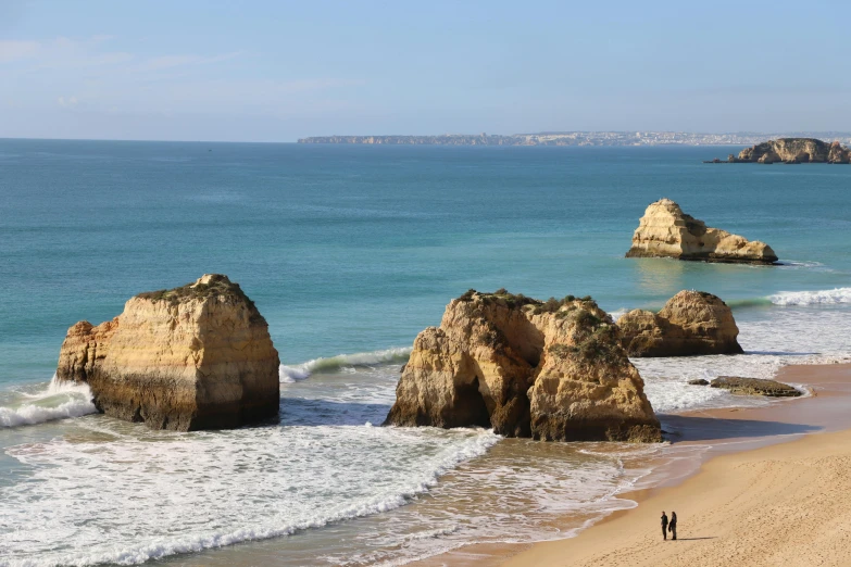 a person is walking on the beach between two large rocks