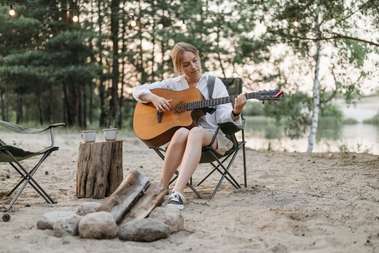 a person sitting in a chair with an acoustic guitar