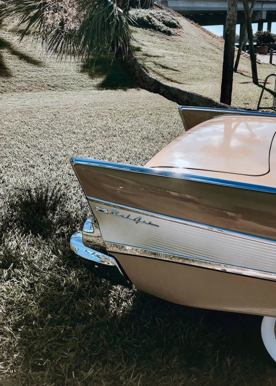 an old - fashioned speed boat sits on some dead grass