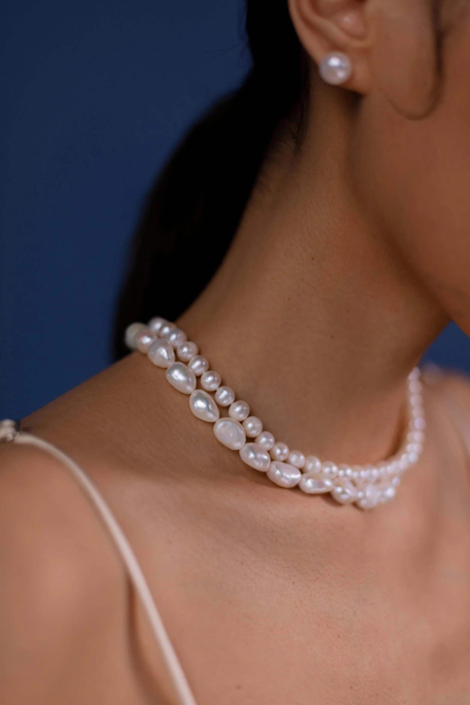 a closeup of a beautiful young woman wearing a pearl necklace