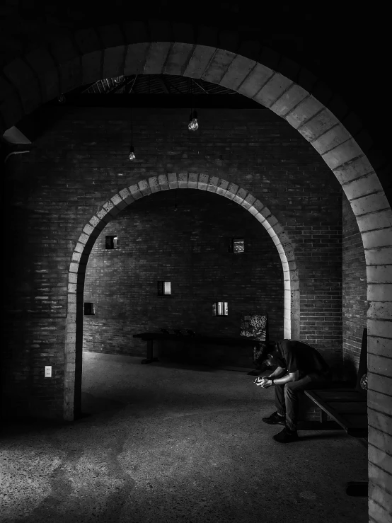 a person sitting on a bench in an archway