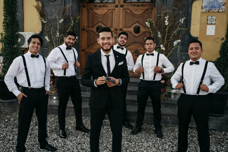 the groom and his groomsmen posing for pictures outside the church door