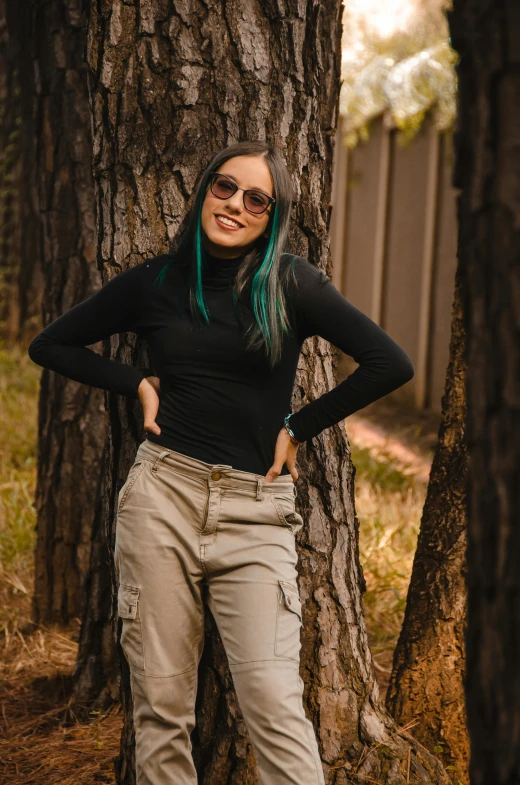 a woman with green hair stands in front of a tree