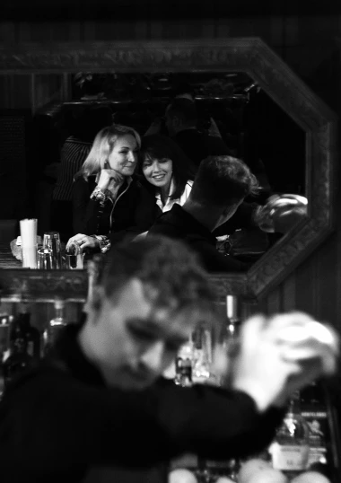 some women at a bar having drinks with some men