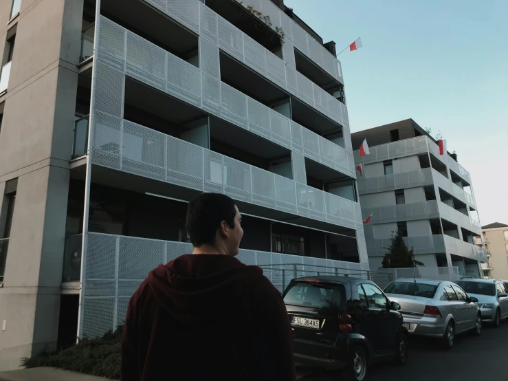 a person is standing in front of a building with a car outside