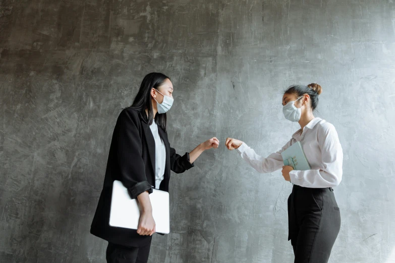 two people in business attire are facing each other as one woman holds out her hand