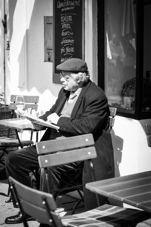 man in front of a restaurant sitting on a bench and writing on a note pad