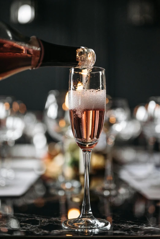 champagne is poured into an elegant glass on top of a table