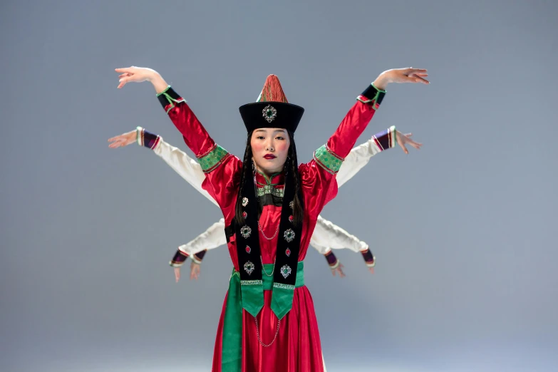 a woman wearing red and green is performing with her hands raised