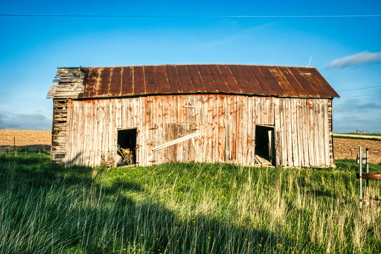 a rustic barn sitting on a lush green grass covered field