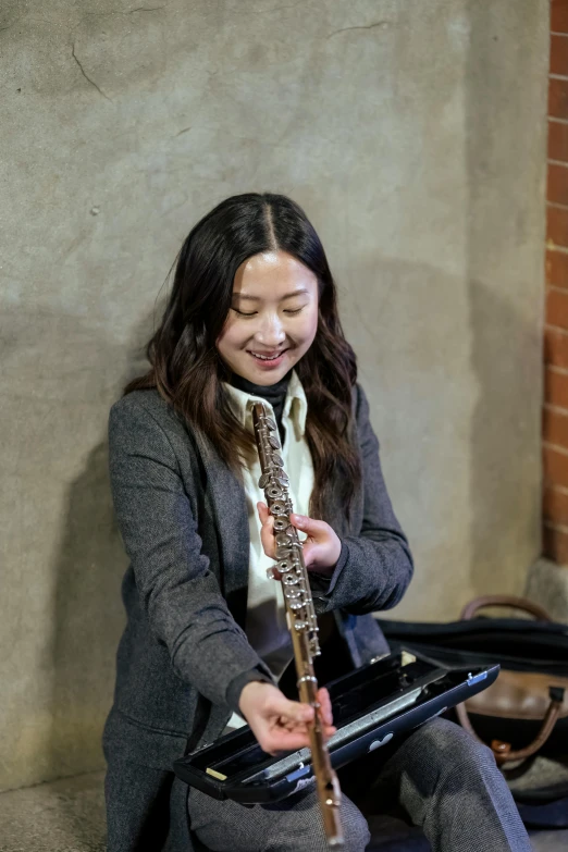 a girl sitting on the ground and playing a wood instrument