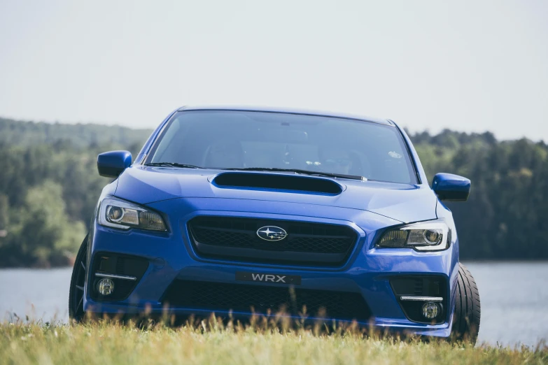 a blue subarunt is parked near water