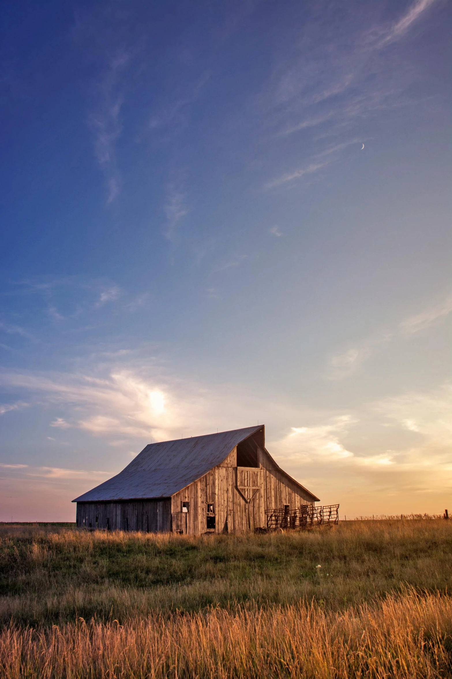 an old barn sitting in a field near the sun