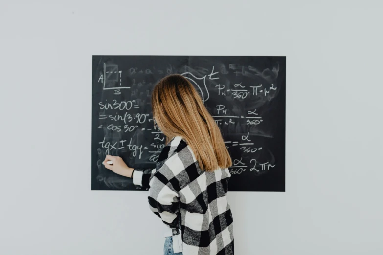 the woman in the black and white sweater is writing on the chalk board