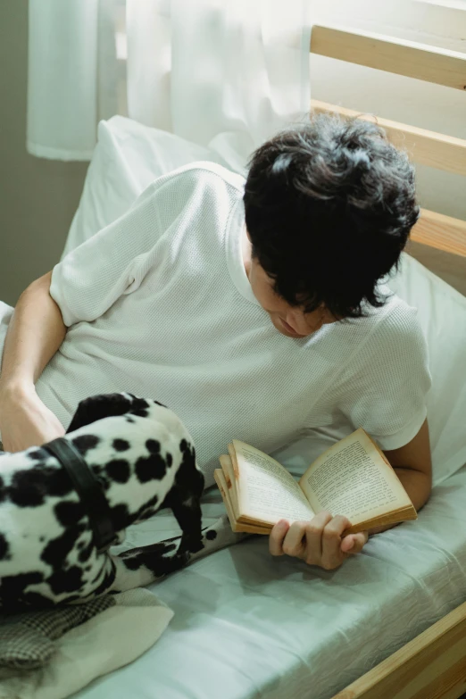 a man reading a book on top of a bed