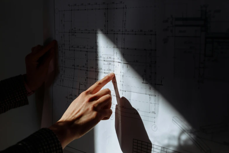 a person holds a piece of paper in front of a drawing on a wall