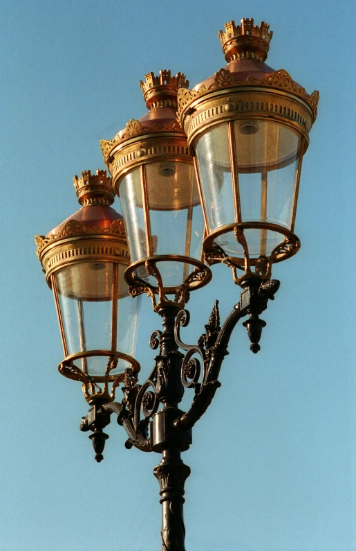 the street lights are gold colored and light up the blue sky