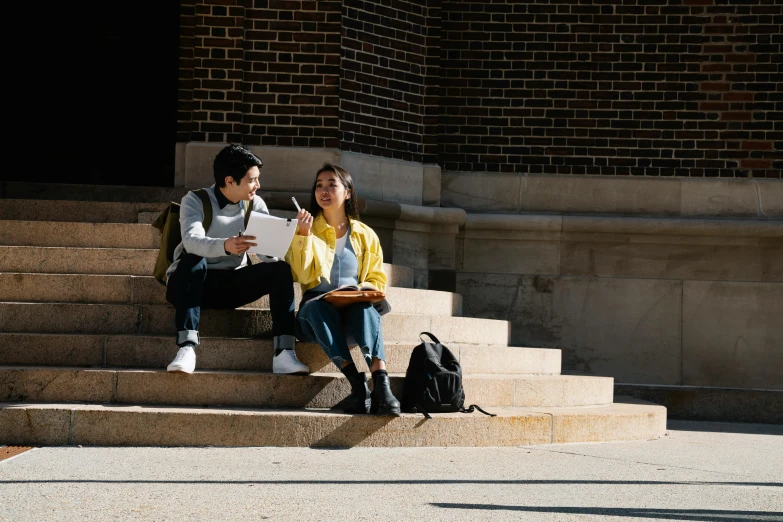 two students sitting on a stone staircase outside