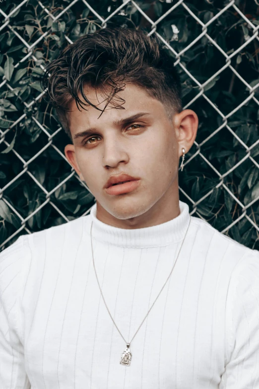 a man posing in front of a chain link fence with tattoos on his face