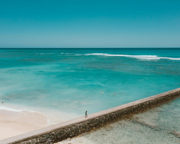 two people walk along the edge of an ocean cliff