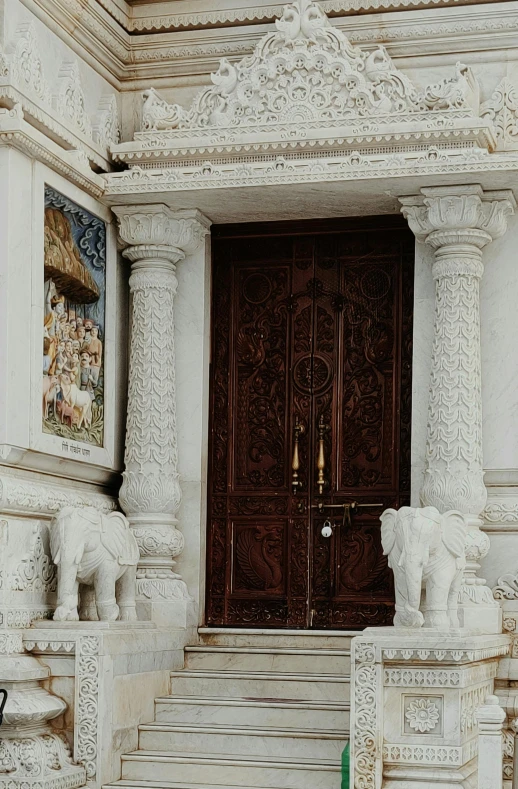 a pair of sculptures stand in front of two large doors