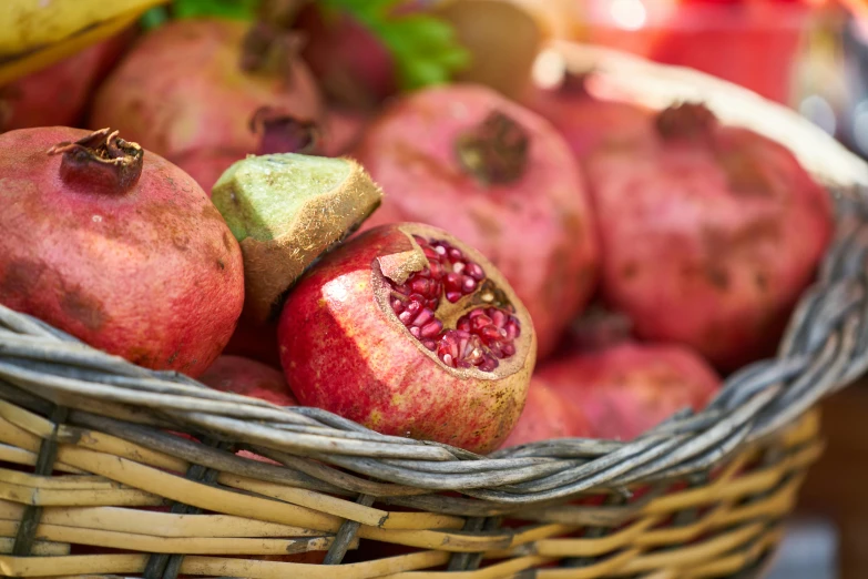 fresh pomegranates are in a wicker basket on display