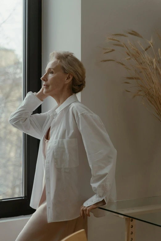 an older woman posing by a window in her apartment