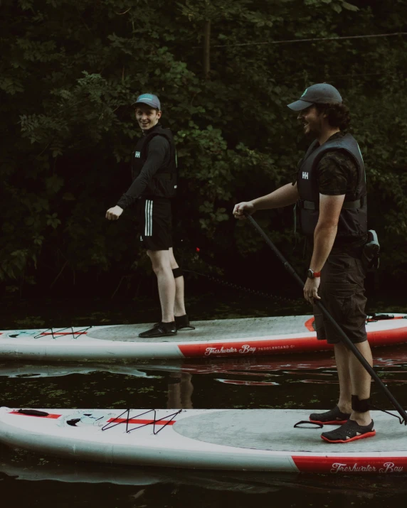 two people standing on two red and white paddle boards