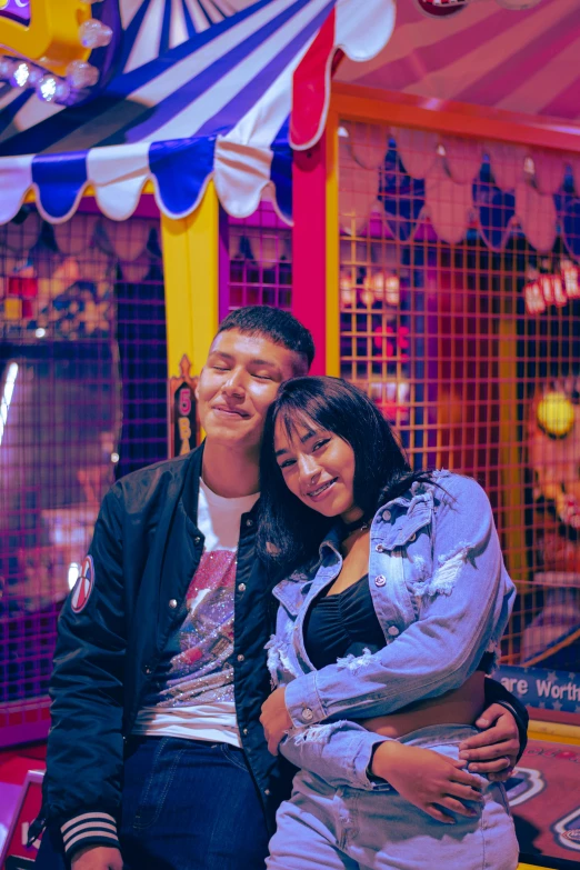 the man and woman are standing together in front of a carnival attraction