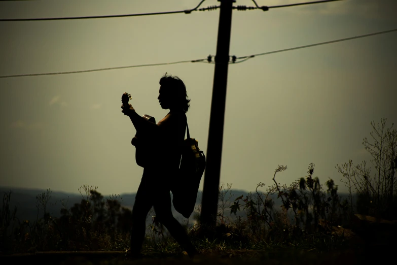 the person is standing in the field playing guitar