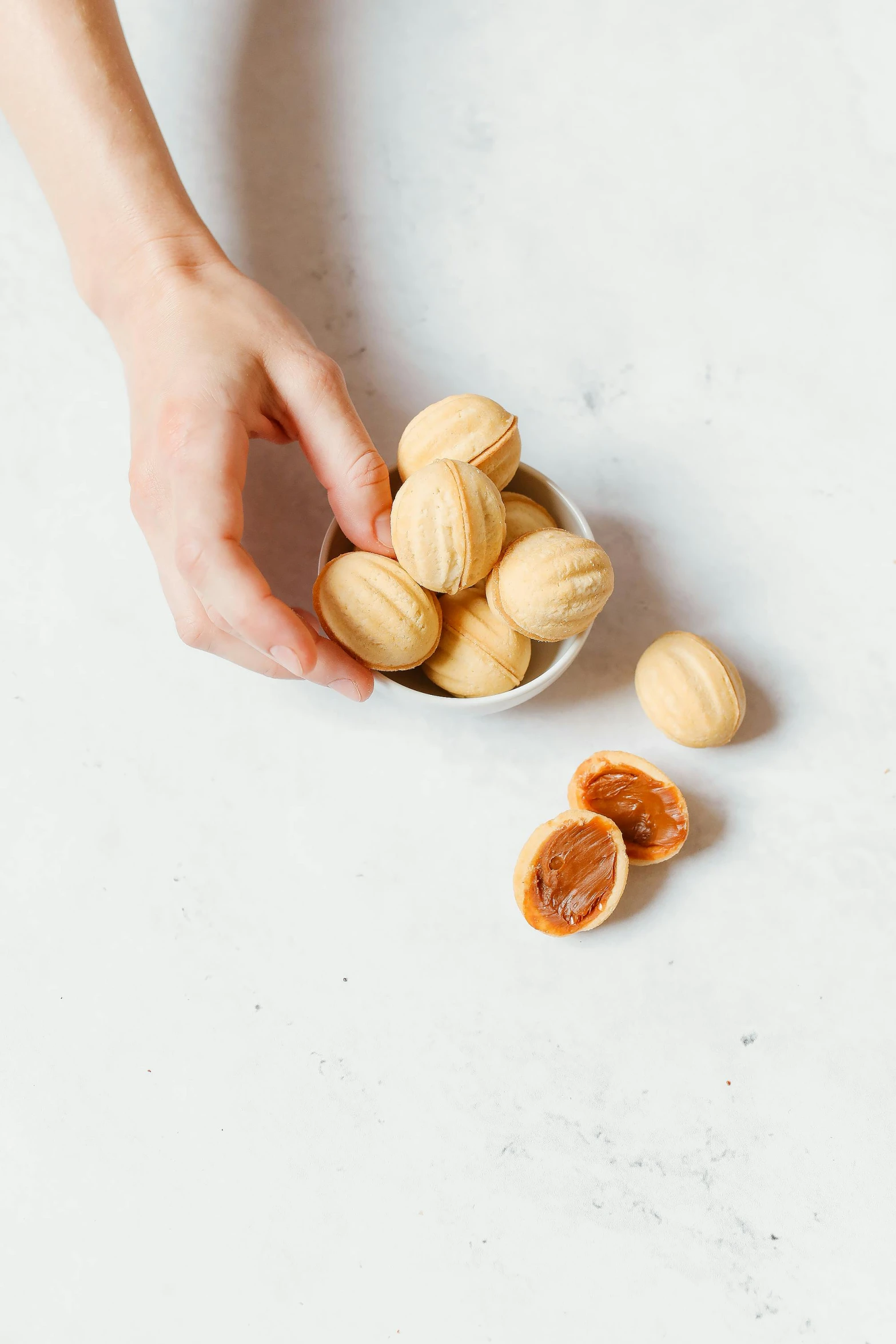 a woman peeling an almonds shell in a small bowl