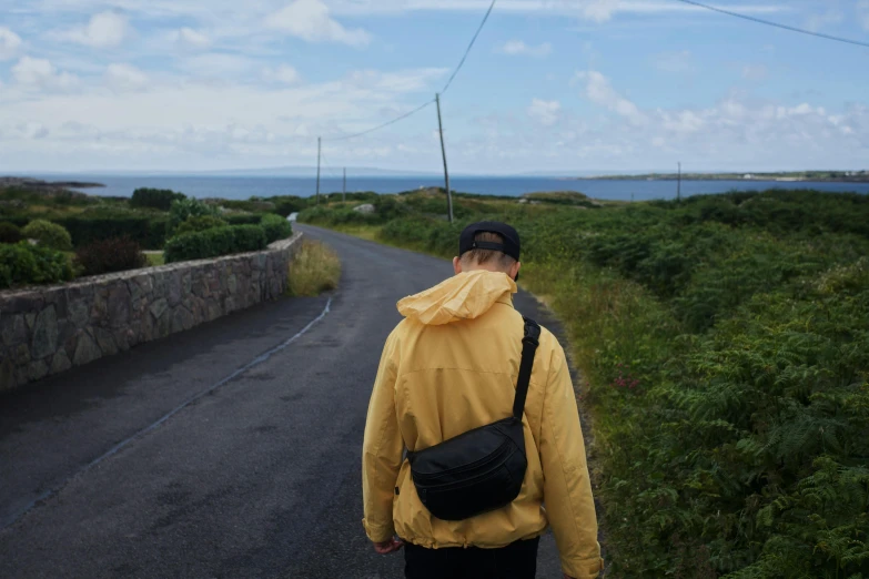 a man carrying a back pack is walking along the road