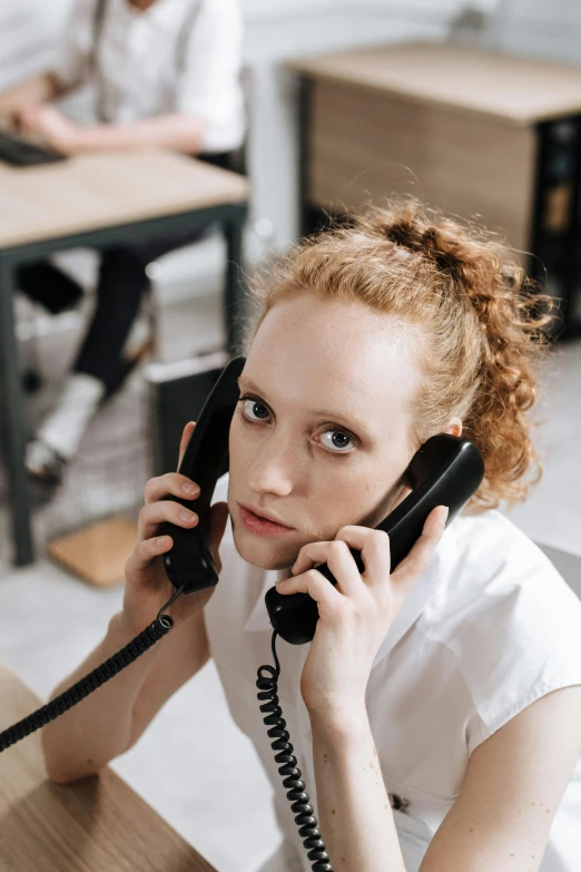 the woman is sitting at a desk talking on the phone