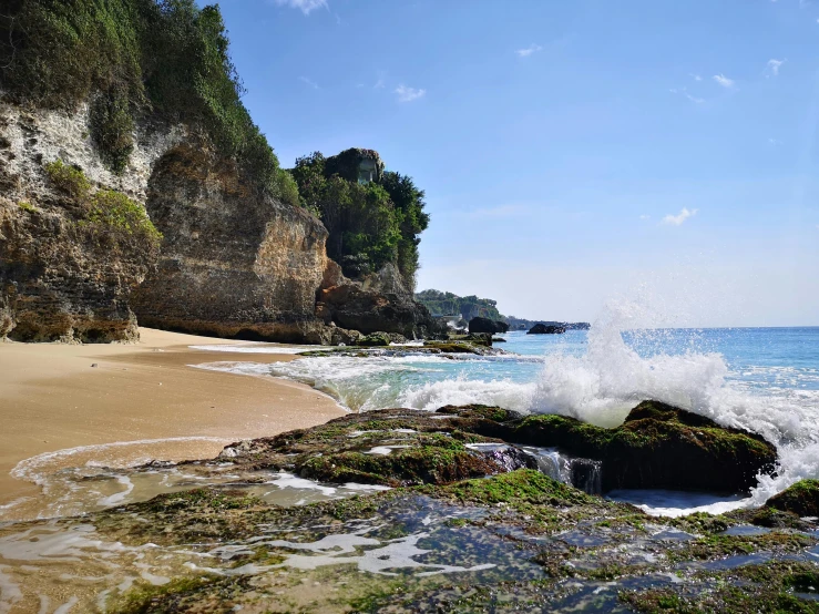 a view of a beach with waves crashing on the rocks