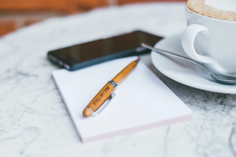 pen, cell phone and notepad sitting on table