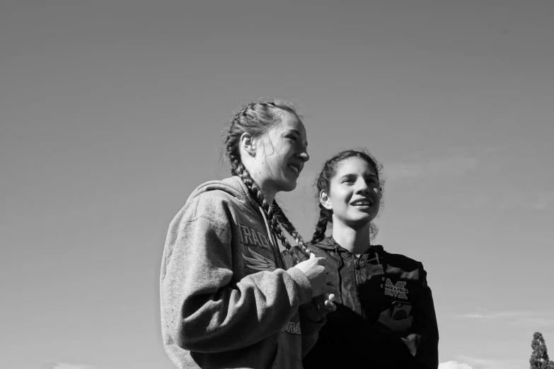 two women are standing together smiling in the park