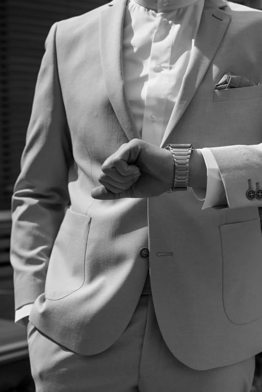 a man in white suit jacket and tie pulling on his lapel