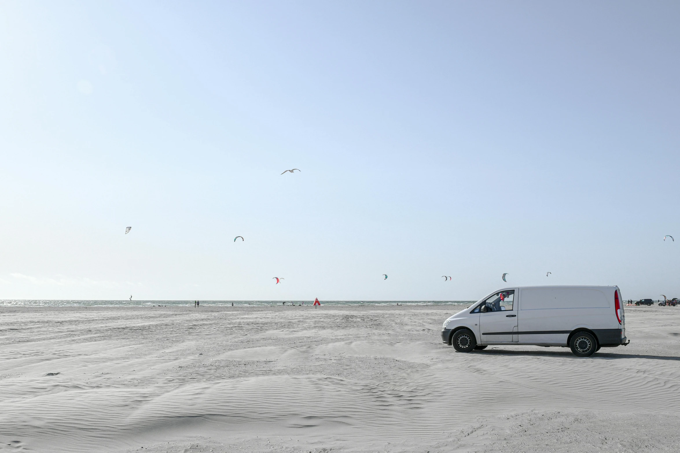 a van sitting on top of a beach next to the ocean