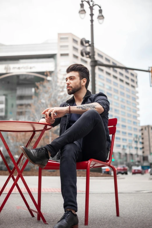 a man sitting in a red chair near a building