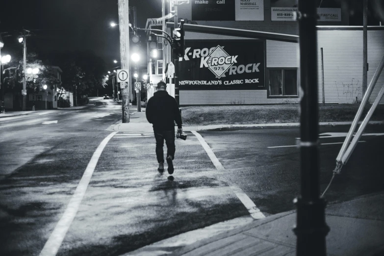 a man is walking down the street at night