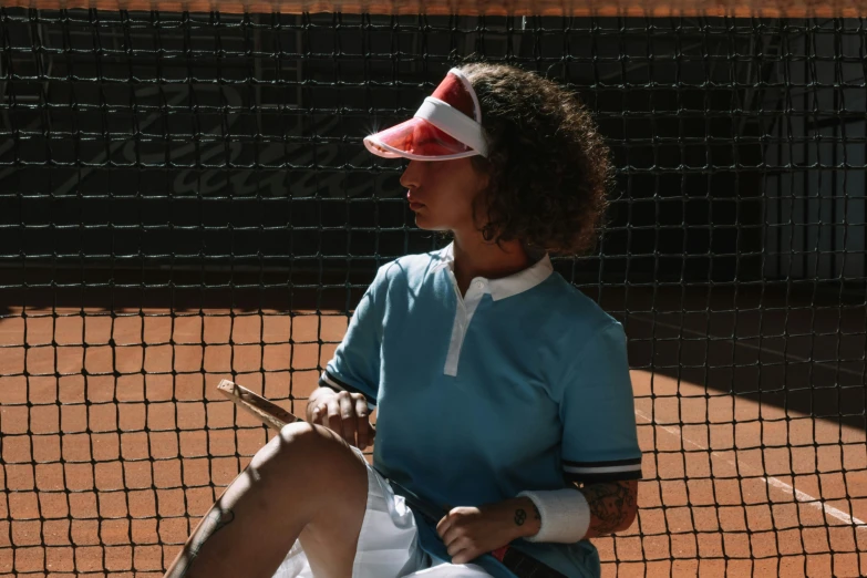 the tennis player sits on the court wearing a hat