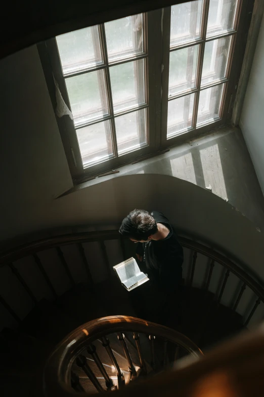 a person standing up a stairwell with a book