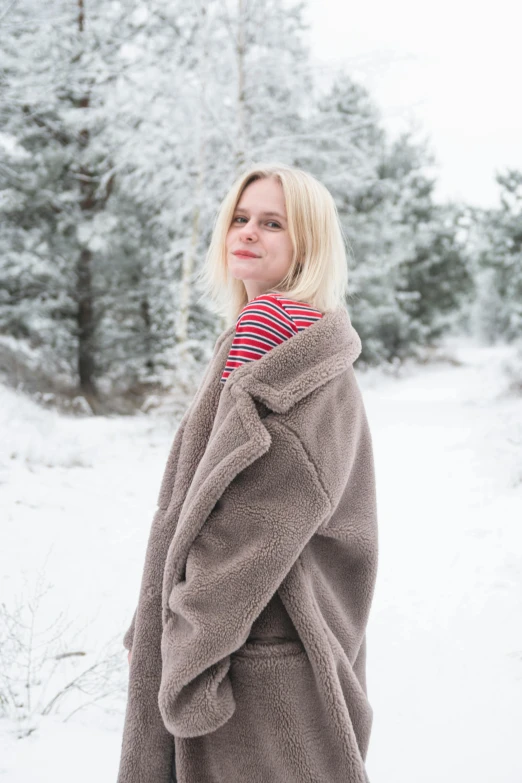 a woman wearing a coat and pants stands in the snow