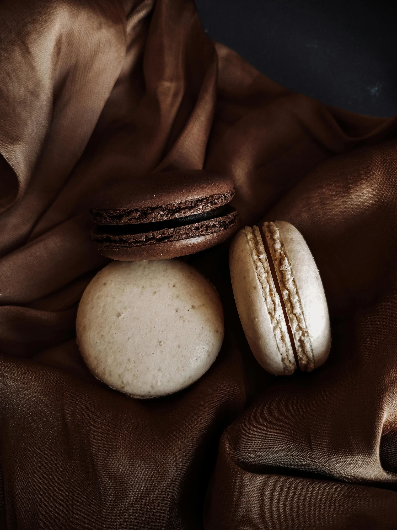 two macaroons laying on a silk blanket