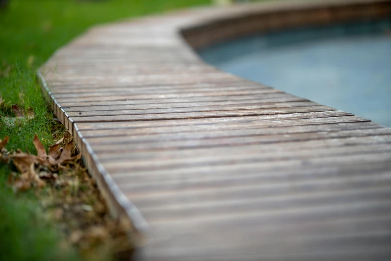 a small wooden walkway next to a pool