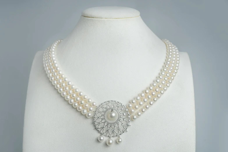 a necklace with two rows of pearls and a brooch on a mannequin