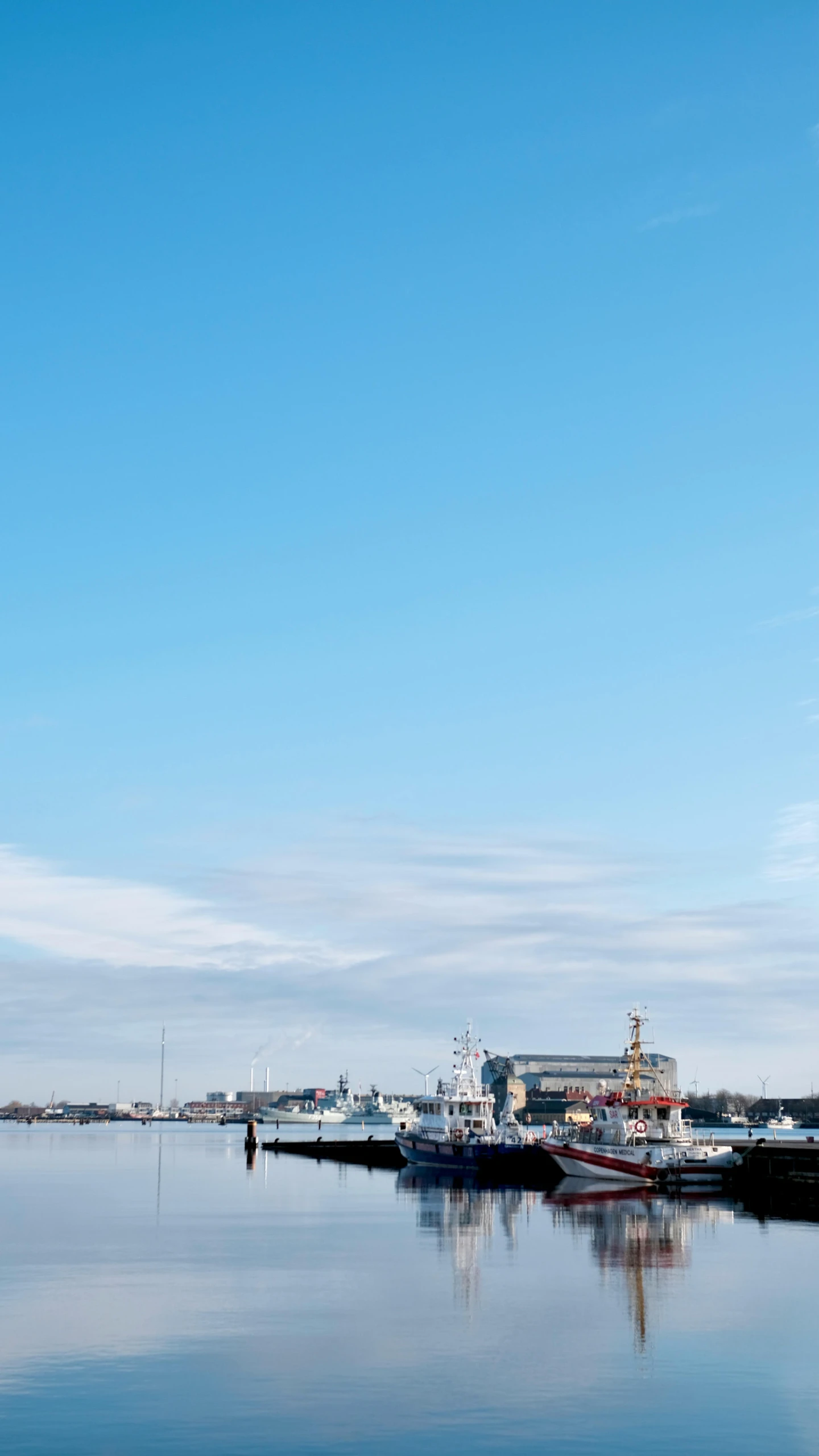 two boats are anchored at the docks on calm water