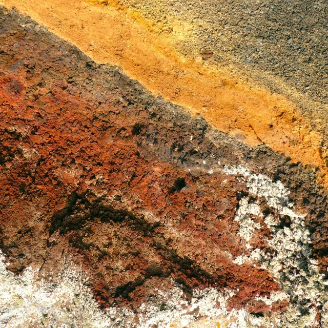 the side of a road painted yellow and gray with dirt and rock layers