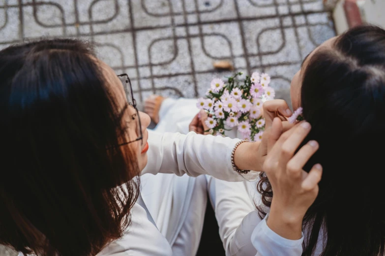 two young ladies looking at soing with flowers in front of them