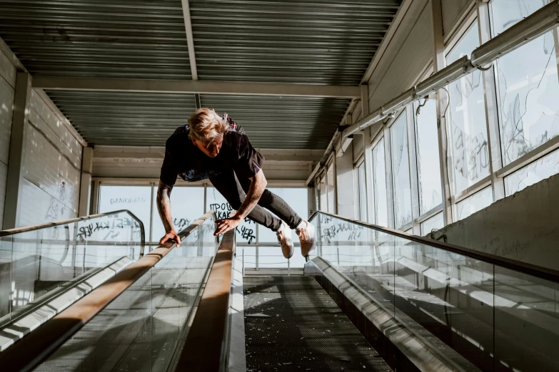 a man wearing black jeans is riding on an escalator